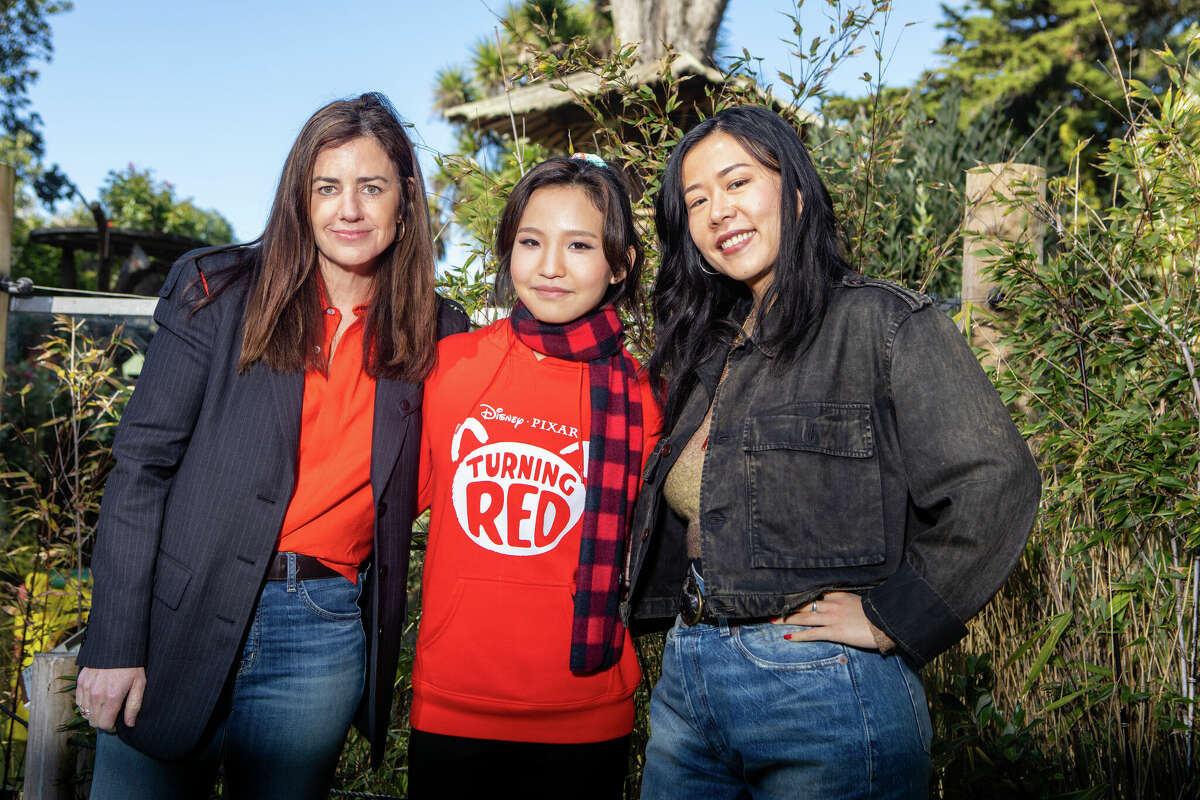 Lindsey Collins, a "Turning Red" producere (balra), Rosalie Chiang, a főszereplő Mei Lee hangja (középen) és Domee Shi rendező (jobbra) pózolnak egy fényképhez a vörös panda ketrece előtt a San Franciscó-i Állatkertben március 11-én. Kép: sfgate.com